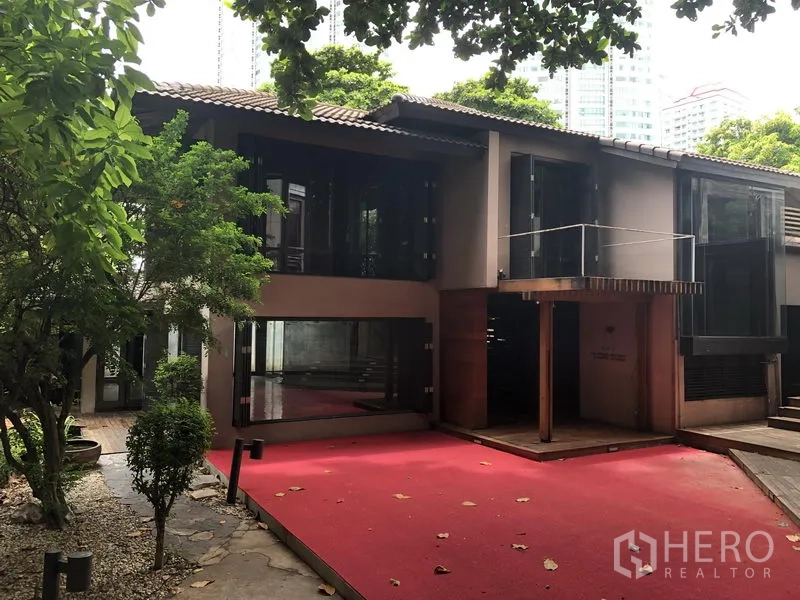 零售空间 出租在Bang Khae, Bangkok - 两层现代建筑，带阳台与红色前庭，树荫浓郁。