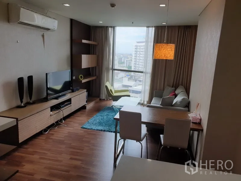 Condominium for rent in Watthana, Bangkok - Bright living and dining area with floor-to-ceiling window, city view, sofa, TV console and wood flooring.