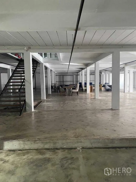 零售空间 出租在Bang Na, Bangkok - 开放楼层带金属楼梯，远端摆放桌椅。