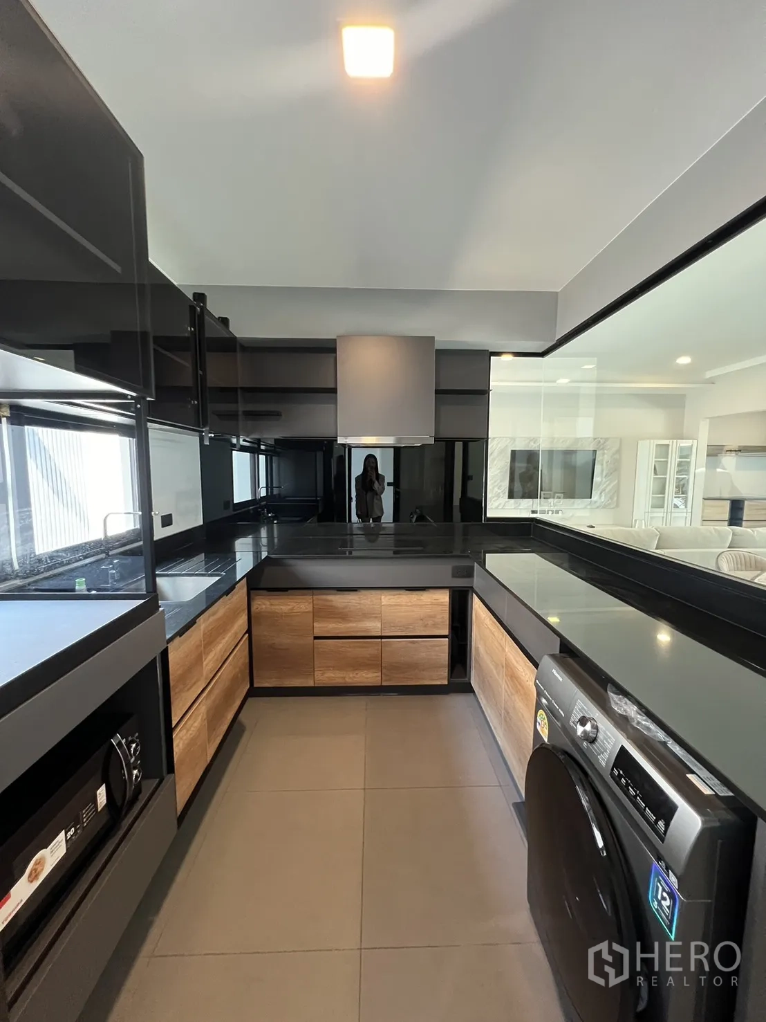 Detached House for rent in Bang Phli, Samut Prakan - U-shaped modern kitchen with black countertops, wood cabinetry and washer.