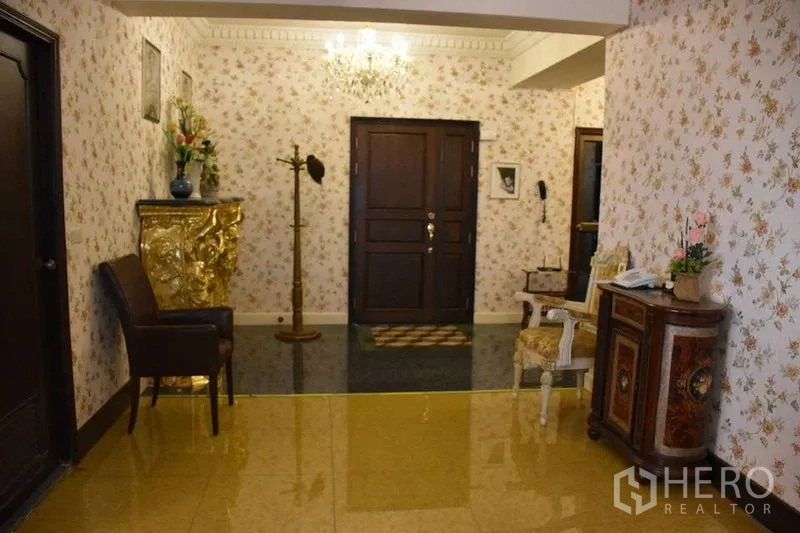 คอนโด ให้เช่าในWatthana, Bangkok - โถงคอนโดสไตล์หรู มีโคมระย้า วอลล์เปเปอร์ลายดอก และประตูไม้สีเข้มในเขตวัฒนา กรุงเทพฯ