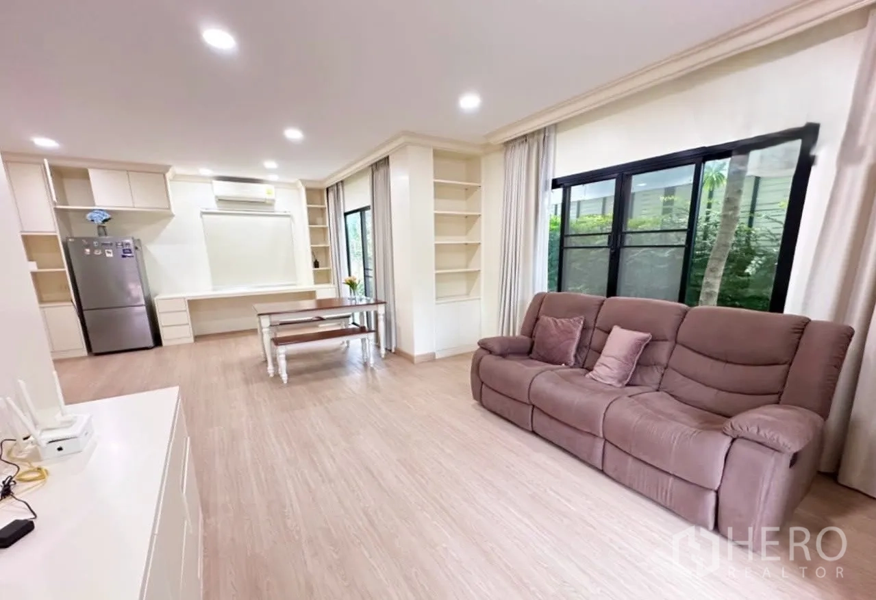 บ้าน ขายในLam Luk Ka, Pathum Thani - โซนนั่งเล่นและทานข้าวแบบเปิดโล่ง โซฟาสีน้ำตาล ตู้บิวท์อิน และหน้าต่างบานใหญ่ติดสวน