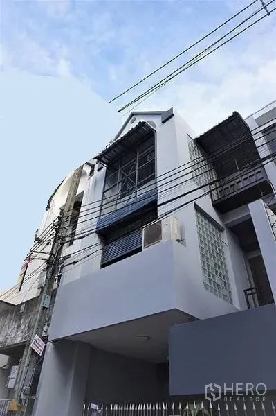 Home Office for rent in Khlong Toei, Bangkok - Modern multi-storey home office facade with large windows and balconies along an urban street.