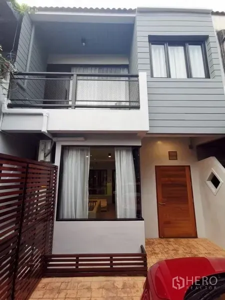 Townhouse for rent in Din Daeng, Bangkok - Two-storey townhouse exterior with balcony, large windows and wooden front door.