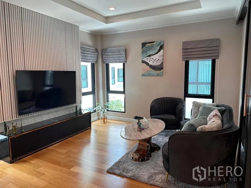 独立式住宅 出租在Prawet, Bangkok - 温馨小客厅，电视、转角窗与沙发组，木地板。