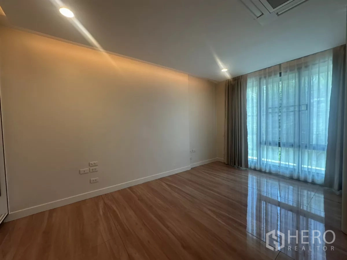 Townhouse for rent in Watthana, Bangkok - Bedroom corner with sheer curtains and tall window for natural light.