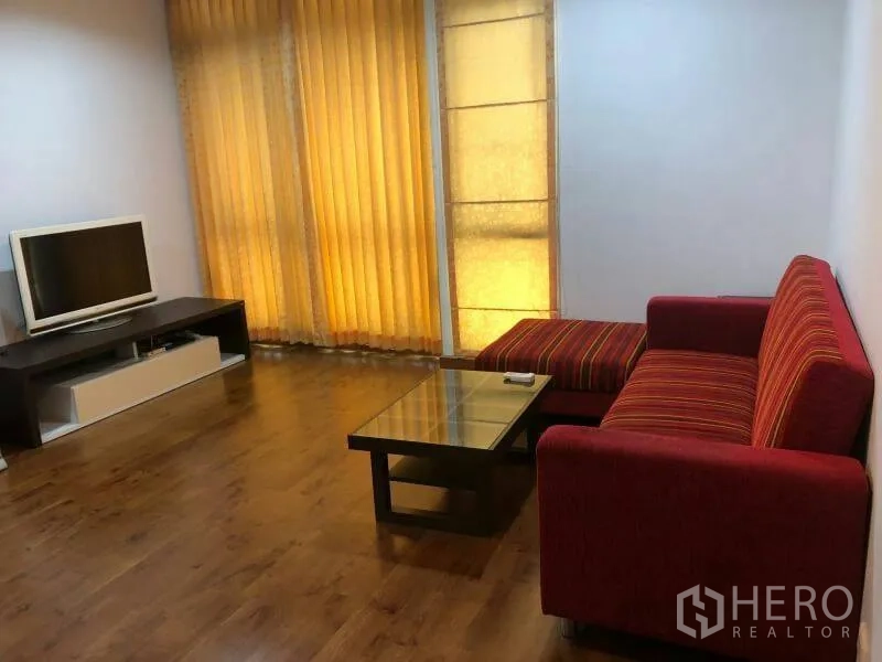 คอนโด ให้เช่าในWatthana, Bangkok - ห้องนั่งเล่นสว่าง โซฟาแดง โต๊ะกลางกระจก ชั้นวางทีวี และม่านสูงถึงเพดานบนพื้นไม้