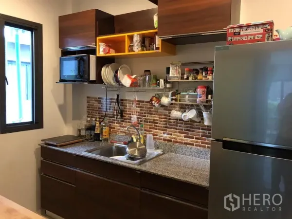 独立式住宅 出租在Saphan Sung, Bangkok - 功能型封闭式厨房，花岗岩台面与砖纹挡板，上方储物柜齐全。