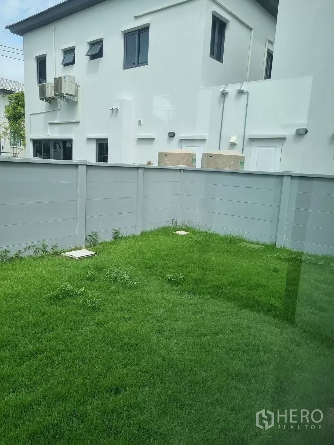 Detached House for rent in Bang Phli, Samut Prakan - Private backyard lawn bordered by a high privacy fence beside neighboring houses.