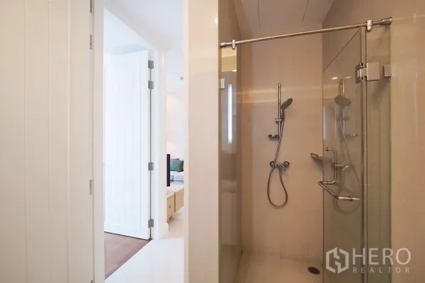 Condominium for rent in Pathum Wan, Bangkok - Glass-enclosed shower with handheld showerhead next to hallway entry.