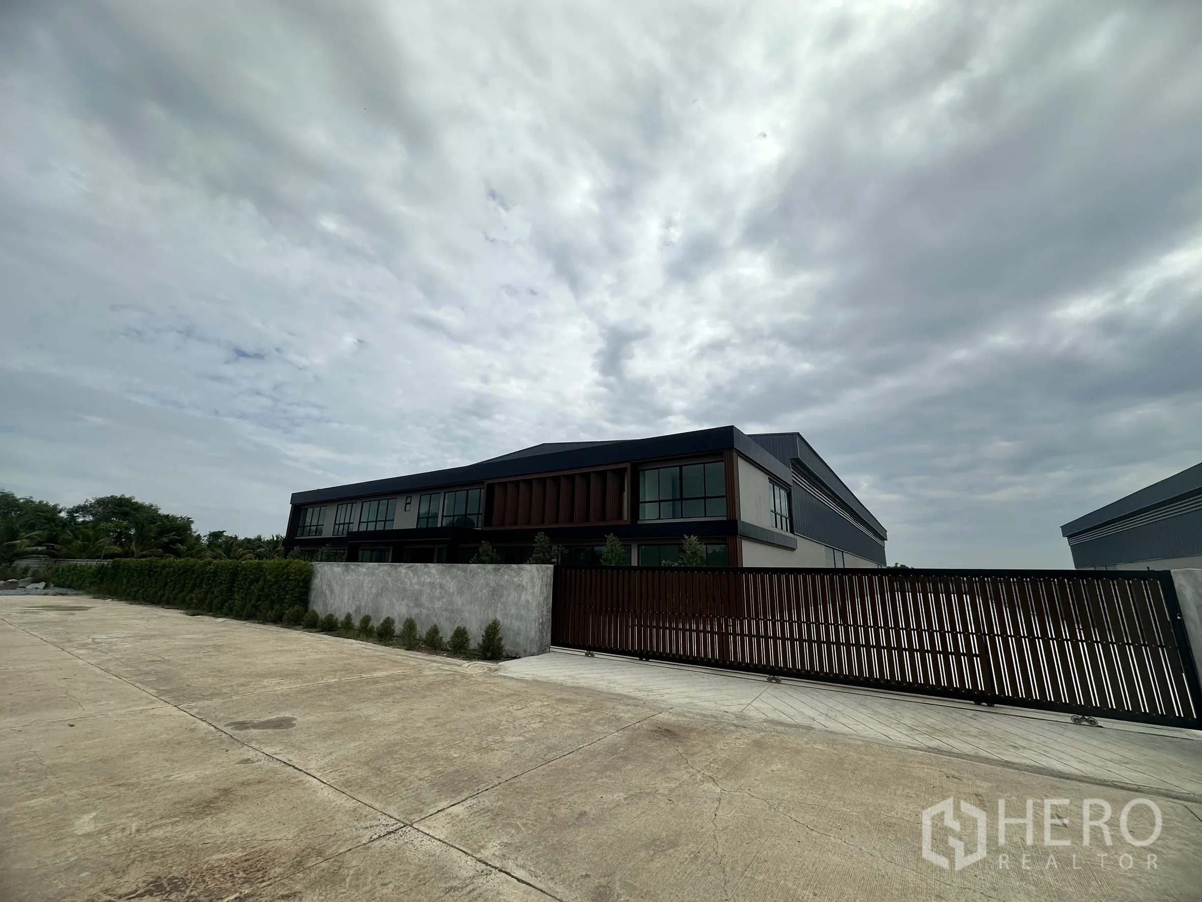 Factory for rent or sale in Bang Len, Nakhon Pathom - Gated entrance with a sliding fence, perimeter wall, and the factory-office building behind.