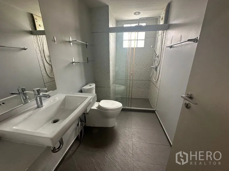 Home Office for rent in Phra Khanong, Bangkok - Modern bathroom with glass shower enclosure, long vanity and large mirror.
