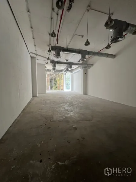 พื้นที่ขายปลีก ให้เช่า - ภายในพื้นที่เชิงพาณิชย์แบบเปลือกอาคาร เพดานสูง เดินท่อดักท์และโคมแขวน พื้นคอนกรีต มีแสงธรรมชาติปลายห้อง