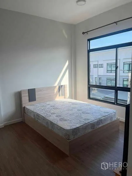 ทาวน์เฮาส์ ให้เช่าในSuan Luang, Bangkok - ห้องนอนมุมพร้อมเตียงคู่ หน้าต่างกระจกขนาดใหญ่ แสงธรรมชาติและพื้นไม้