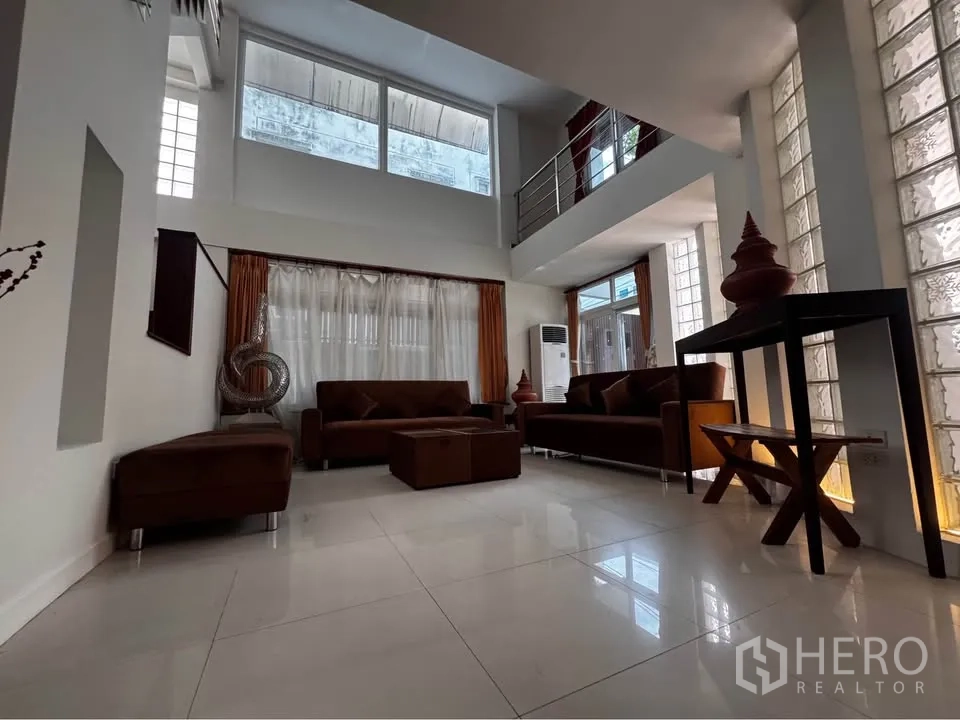 ทาวน์เฮาส์ for rent in Huai Khwang, Bangkok - ห้องนั่งเล่นชั้นล่างเพดานสูง หน้าต่างบานใหญ่และโซฟาชุด.