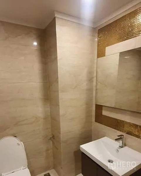 零售空间 出租在Watthana, Bangkok - 现代化卫生间，米色石纹瓷砖，墙面镜与白色洗手台，金色马赛克点缀