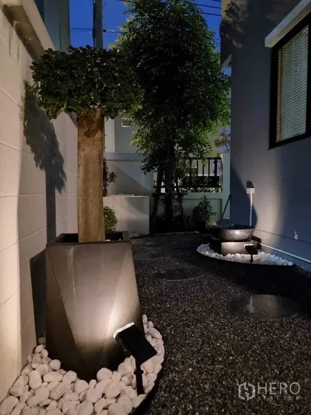 独立式住宅 出售在Khan Na Yao, Bangkok - 侧院砾石小径，景观灯照射花盆与树木。