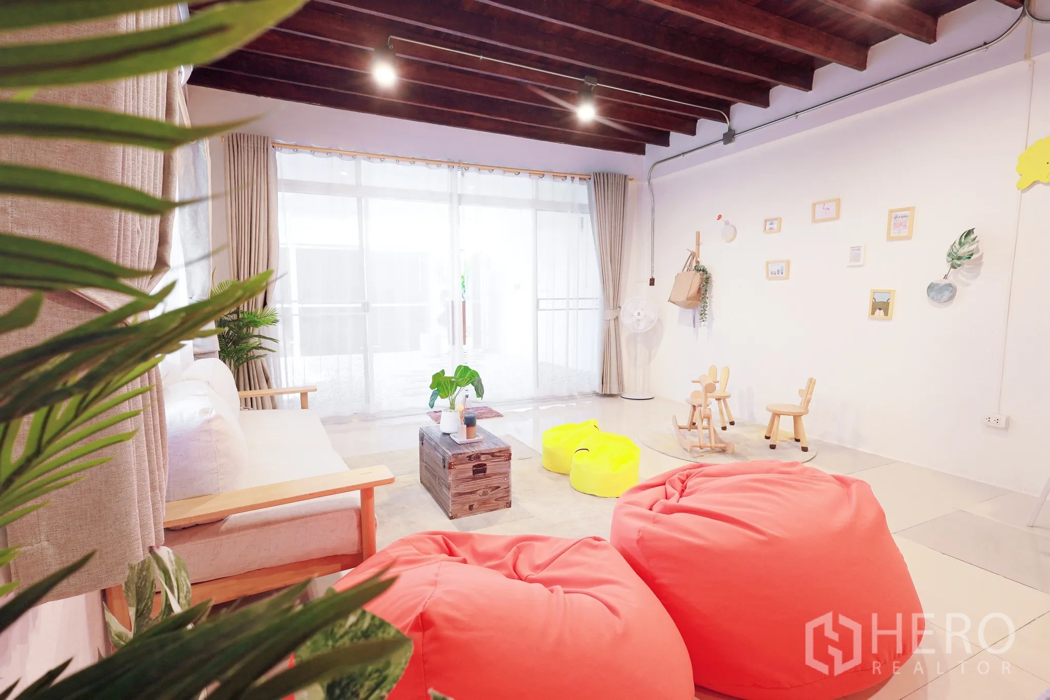 Townhouse for rent in Din Daeng, Bangkok - Family living space with plants and playful seating beneath exposed timber ceiling beams.