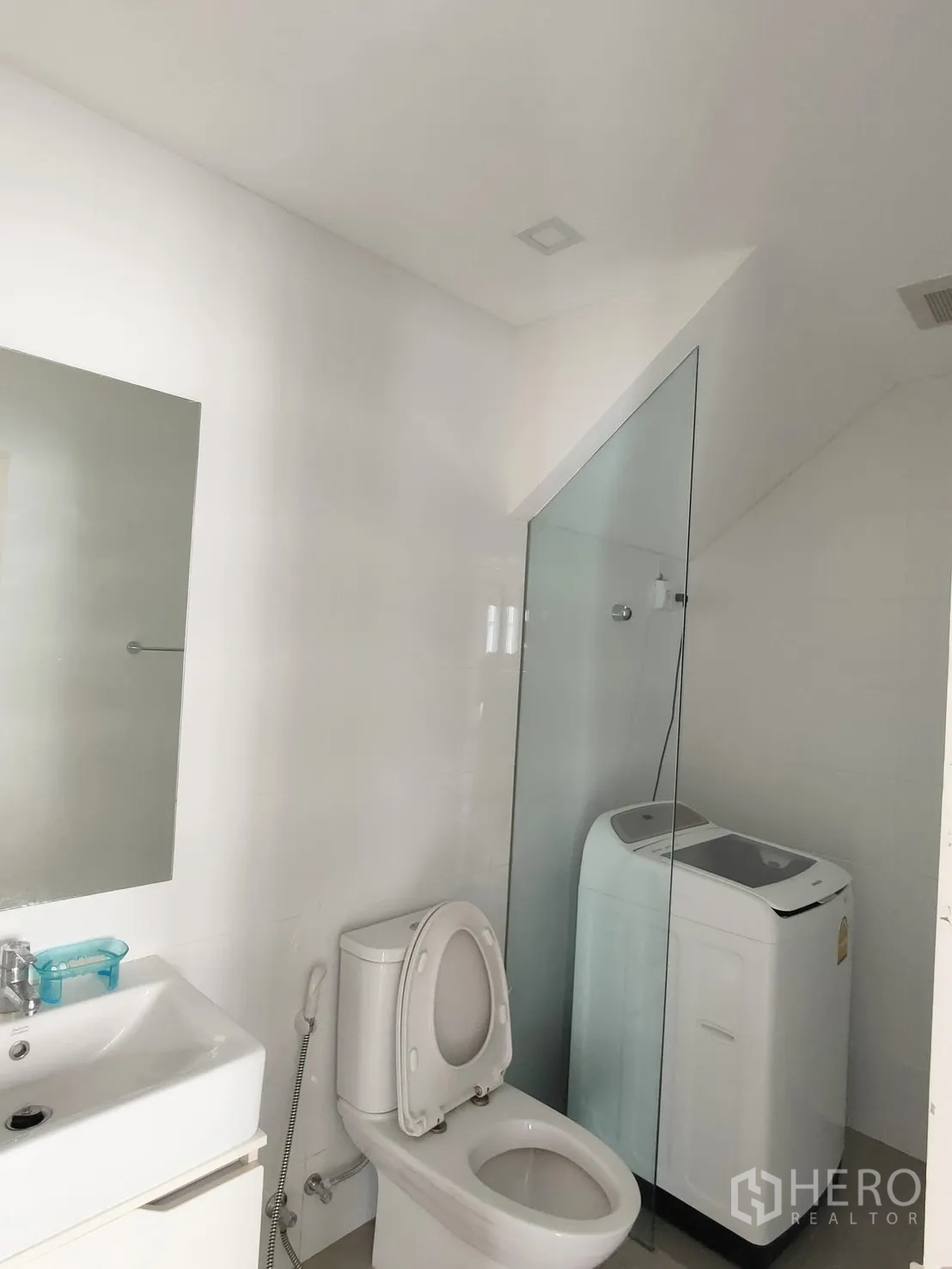 Townhouse for rent in Saphan Sung, Bangkok - Bright bathroom with vanity, toilet, glass-enclosed shower and top-load washing machine.