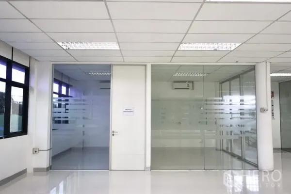 Office Space for rent in Lat Krabang, Bangkok - Glass-partitioned meeting rooms with frosted stripes and a central white door inside a clean office.