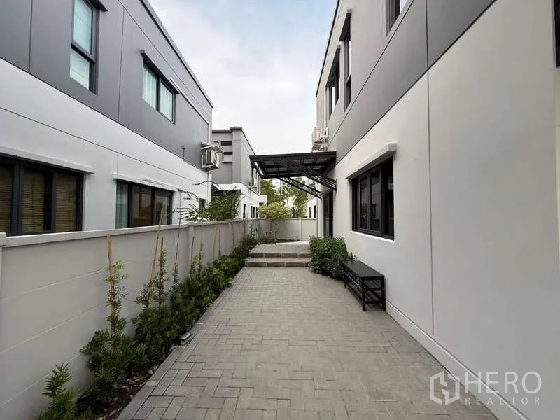 Detached House for sale in Bang Phli, Samut Prakan - Side walkway between houses with paver path and low garden beds.