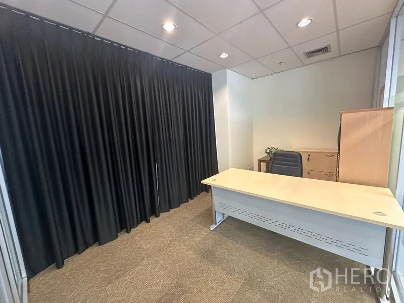 办公空间 出租在Bang Rak, Bangkok - 经理室配办公桌、储物柜与深色窗帘。