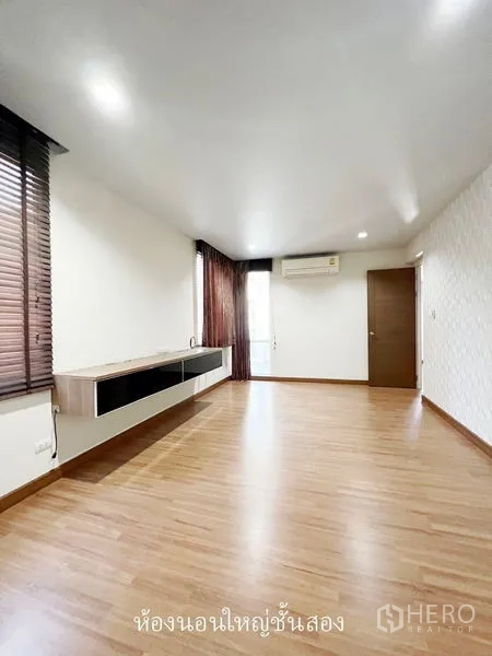 Townhouse for rent or sale in Don Mueang, Bangkok - Second-floor bedroom with built-in media shelf, air conditioner and blinds.