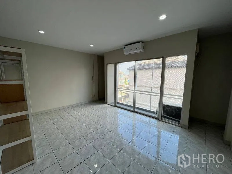 联排别墅 for rent in Phra Khanong, Bangkok - 明亮的瓷砖房间，带推拉玻璃门和壁挂空调。