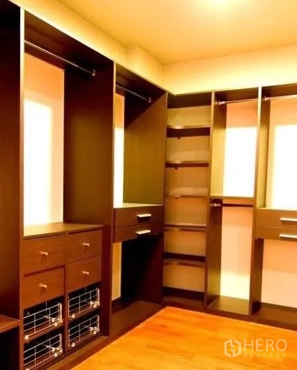 Detached House for rent in Khlong Toei, Bangkok - Spacious walk‑in closet with built‑in dark wood shelving, drawers and hanging space.