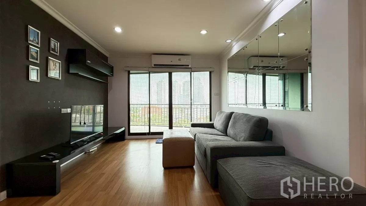 คอนโด ขายในYan Nawa, Bangkok - ห้องนั่งเล่นพร้อมโซฟาสีเทา ชั้นวางทีวี ผนังกระจก และประตูกระจกออกระเบียงวิวเมือง