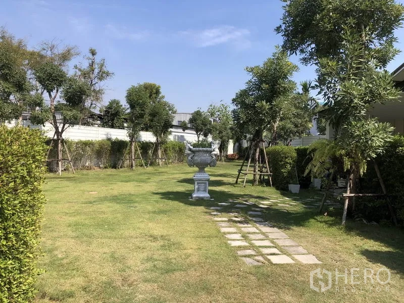 Townhouse for rent in Saphan Sung, Bangkok - Leafy communal garden with lawn, pathway and trees inside the estate