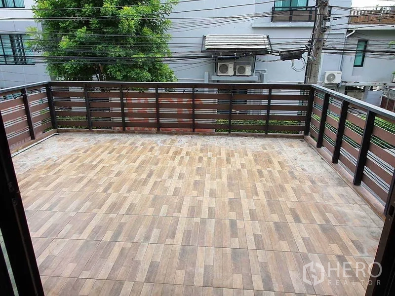 Townhouse for sale in Khlong Toei, Bangkok - Expansive tiled terrace with metal railing overlooking neighboring homes.