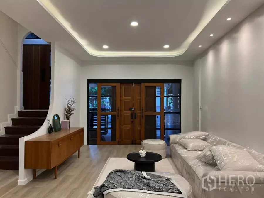 Townhouse for rent - Bright living room with recessed ceiling lights, wooden front doors and a staircase in a newly renovated townhouse.
