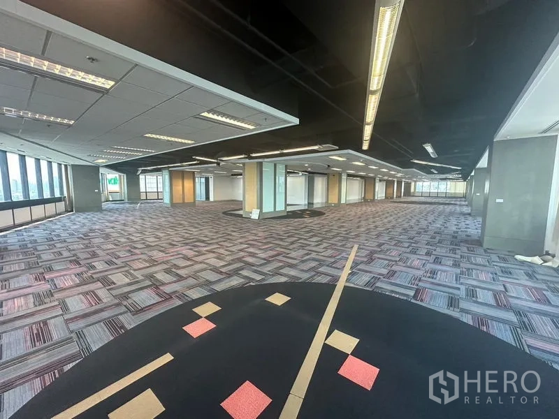 Office Space for rent in Khlong Toei, Bangkok - Large office floor with distinctive patterned carpet and city-facing windows.