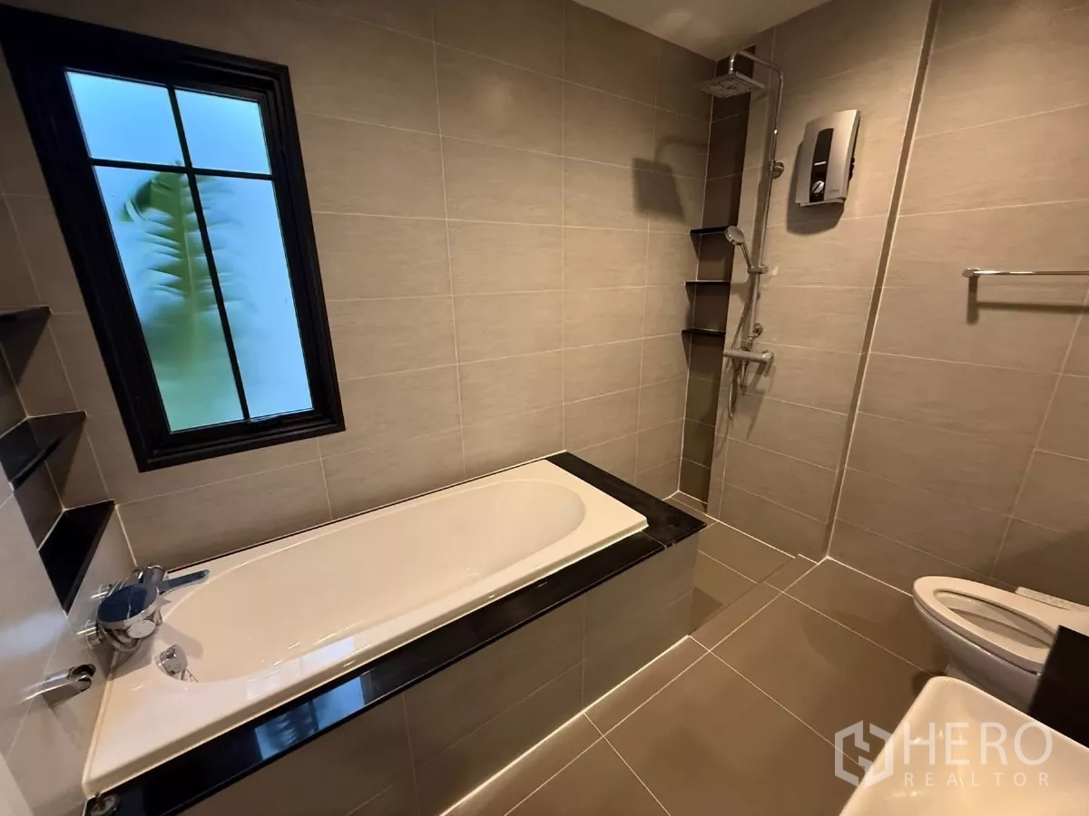 Detached House for rent or sale in Bang Phli, Samut Prakan - Bathroom with bathtub, separate rain shower and frosted window in neutral tiles.