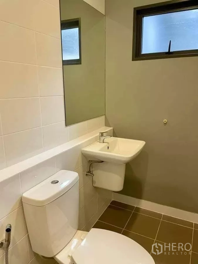 Townhouse for rent in Bang Phli, Samut Prakan - Clean bathroom with toilet, wall mirror, sink and frosted window.