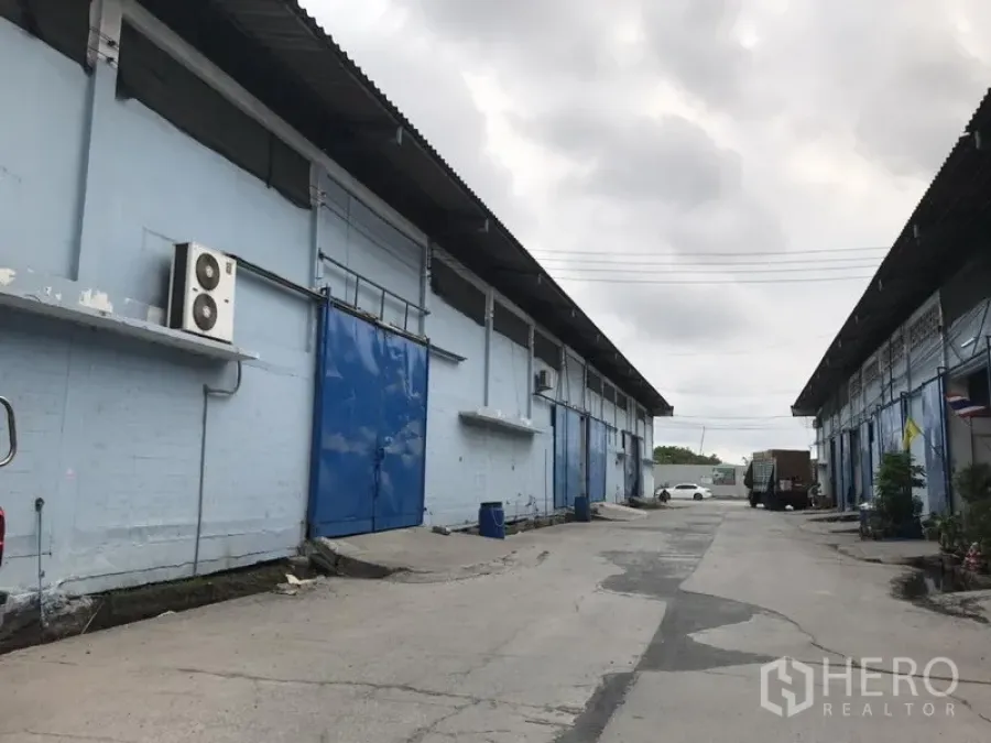 คลังสินค้า ให้เช่าในBang Phli, Samut Prakan - ทางสัญจรระหว่างอาคารโกดังสีฟ้าอ่อน ประตูบานเลื่อนสีน้ำเงิน รองรับรถบรรทุก