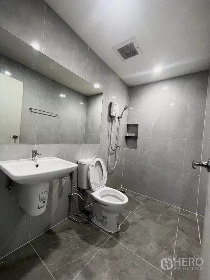 ทาวน์เฮาส์ ให้เช่าในSamut Prakan - ห้องน้ำกระเบื้องสีเทา กระจกยาว ฝักบัว และโถสุขภัณฑ์