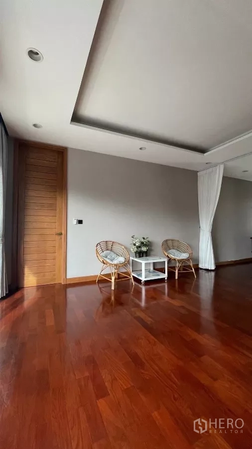 Detached House for rent in Prawet, Bangkok - Upper lounge with rattan chairs, side table and polished wood floor.