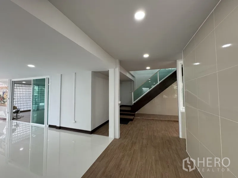 Townhouse for sale in Bueng Kum, Bangkok - Hallway leading to staircase with wood floors and sliding glass partitions.