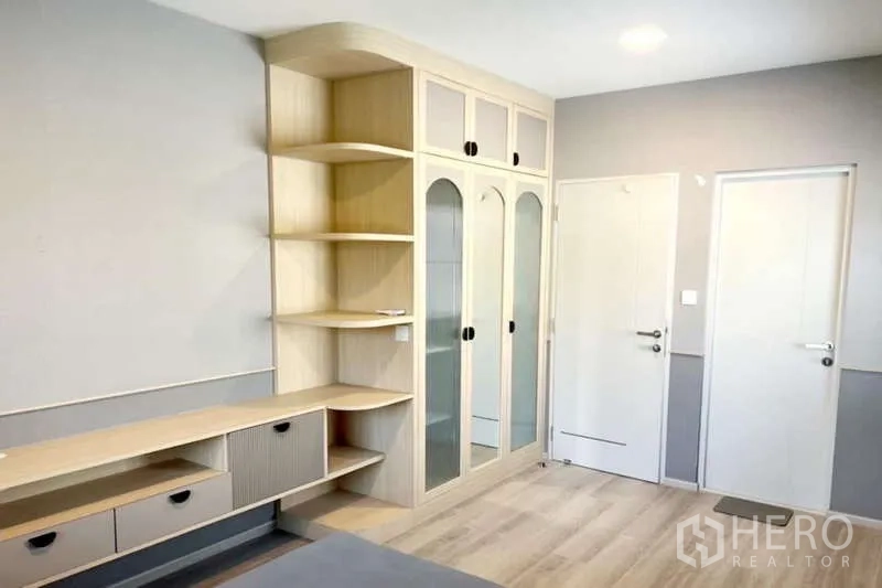 Detached House for rent in Prawet, Bangkok - Bedroom corner showing arched glass wardrobe and open shelves.