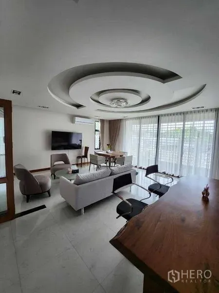 บ้าน ขายในPhra Khanong, Bangkok - ห้องนั่งเล่นสว่างเพดานลวดลายวงกลม ผ้าม่านสูง โซฟา และเคาน์เตอร์บาร์