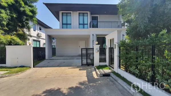 Detached House for sale in Prawet, Bangkok - Front facade with secure fence, driveway and covered two-car carport.
