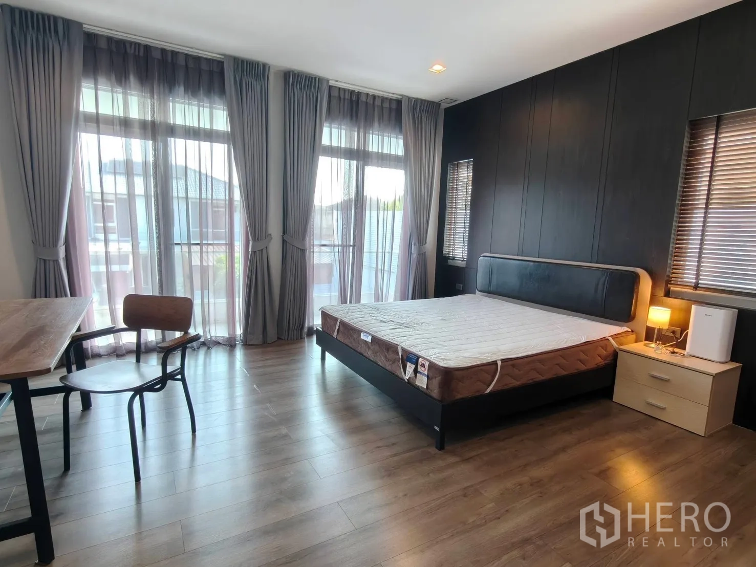 独栋房屋 for rent or sale in Bang Phli, Samut Prakan - 宽敞主卧，带书桌、床头柜与落地窗帘。