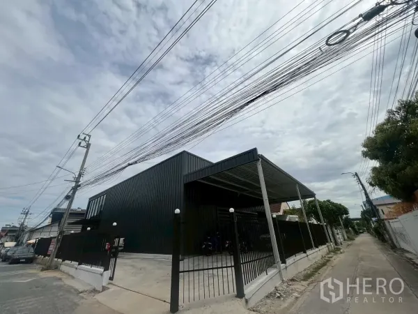 Warehouse for rent in Bang Na, Bangkok - Street view of a modern black metal warehouse with gated entrance and covered loading bay.