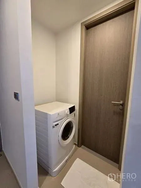 คอนโด ให้เช่าในPhaya Thai, Bangkok - มุมซักผ้าขนาดกะทัดรัดพร้อมเครื่องซักผ้าฝาหน้า อยู่ข้างประตูไม้