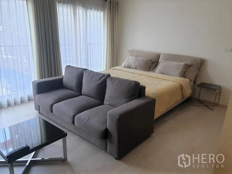 คอนโด ให้เช่าในKhlong Toei, Bangkok - มุมพื้นที่นอนสว่างพร้อมเตียงใหญ่ โซฟา และหน้าต่างกระจกเต็มบาน