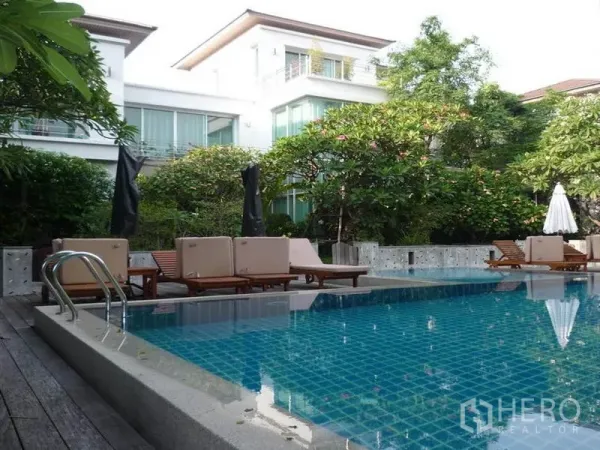 独立式住宅 出租在Khan Na Yao, Bangkok - 花园环绕的泳池，配躺椅，旁边为现代独栋住宅