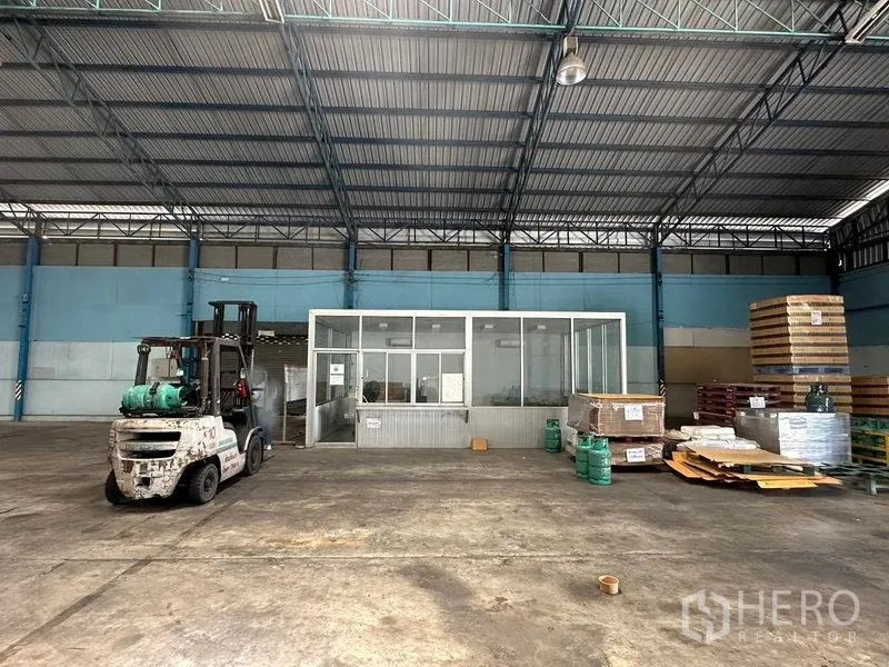 货栈 出租在Bang Pa-in, Phra Nakhon Si Ayutthaya - 仓库内的玻璃隔断办公室，旁有托盘与物料堆放。