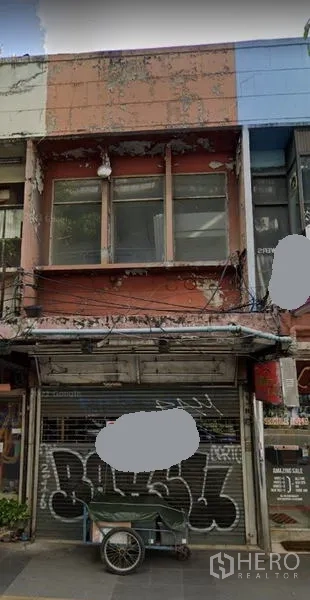 อาคารพาณิชย์ ให้เช่าในKhlong Toei, Bangkok - ด้านหน้าอาคารพาณิชย์ 2 ชั้น ประตูม้วนโลหะ ผนังเก่า และสายไฟเหนือทางเท้าบนถนนในเมือง